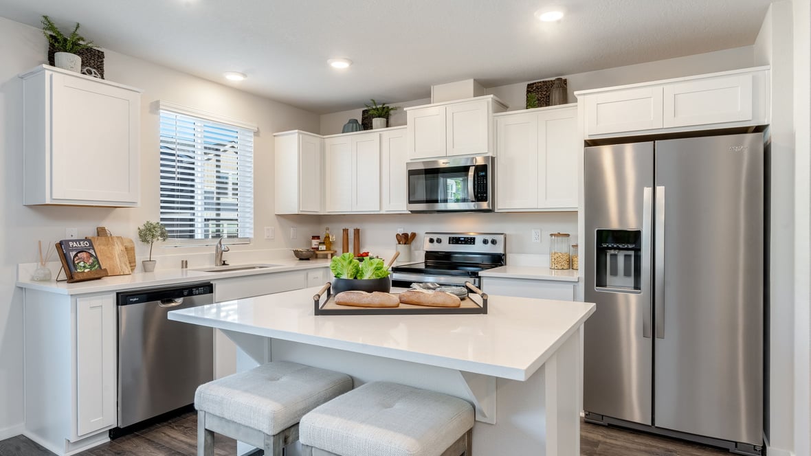 Kitchen with shaker cabinets, quartz counters, stainless steel appliances, pantry, and an island with a breakfast bar