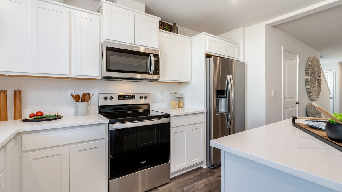 Kitchen with shaker cabinets, quartz counters, stainless steel appliances, pantry, and an island with a breakfast bar