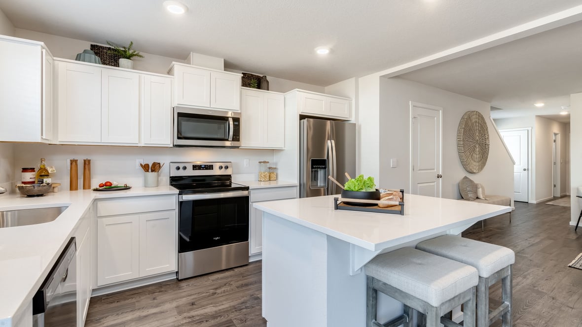Kitchen with shaker cabinets, quartz counters, stainless steel appliances, pantry, and an island with a breakfast bar