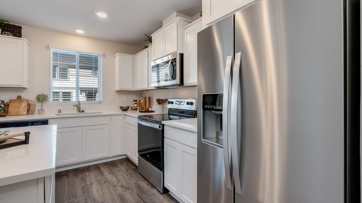 Kitchen with shaker cabinets, quartz counters, stainless steel appliances, pantry, and an island with a breakfast bar