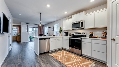 u-shaped kitchen with stainless steel appliances, quartz countertops, and a full size pantry
