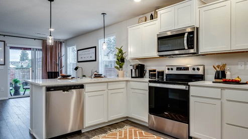 u-shaped kitchen with stainless steel appliances, quartz countertops, and a full size pantry