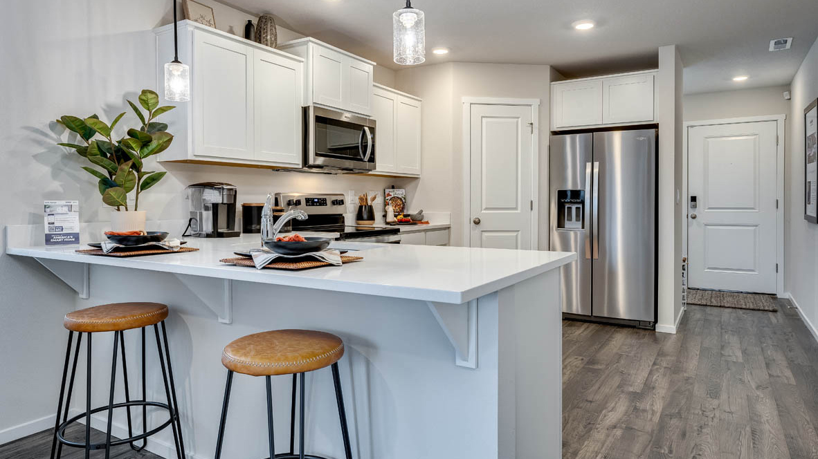 U-shaped kitchen with shaker cabinets, quartz counters, stainless steel appliances, pantry, and a breakfast bar