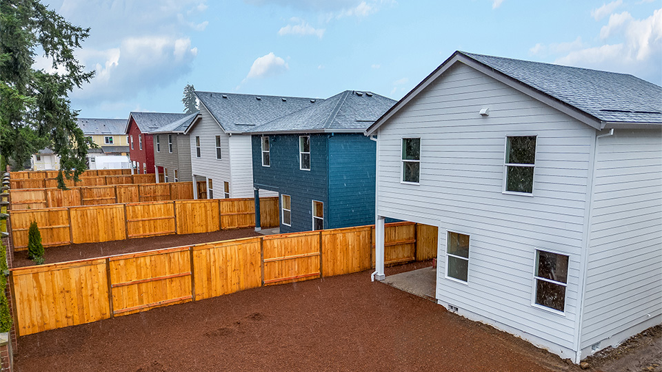fully fenced backyard with bark chips and a patio