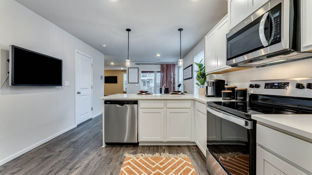 U-shaped kitchen with shaker cabinets, quartz counters, stainless steel appliances, pantry, and a breakfast bar