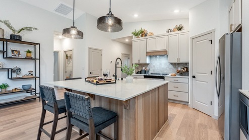 Kitchen with shaker cabinets, quartz counters, stainless steel appliances, pantry, and an island with a breakfast bar