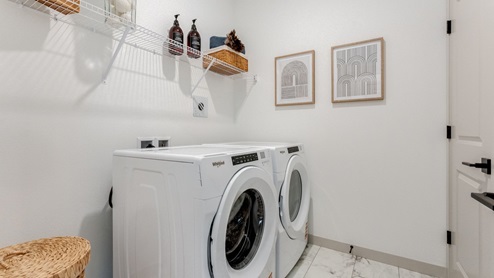 Laundry room with built-in shelves and washer and dryer hookups