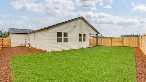 fully fenced backyard with sod lawn and a patio