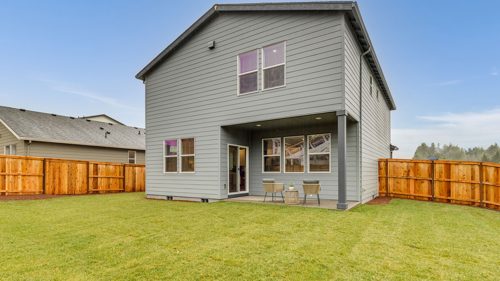 fully fenced backyard with sod lawn and a patio