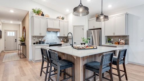 Kitchen with shaker cabinets, quartz counters, stainless steel appliances, pantry, and an island with a breakfast bar