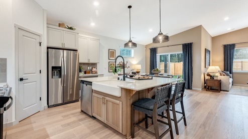 Kitchen with shaker cabinets, quartz counters, stainless steel appliances, pantry, and an island with a breakfast bar