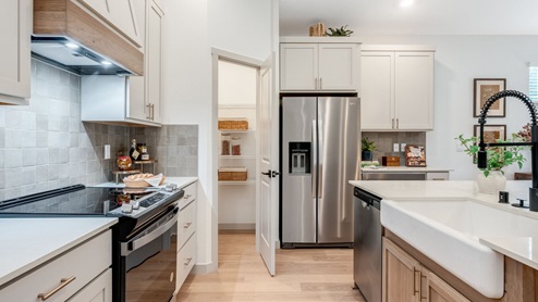 Kitchen with shaker cabinets, quartz counters, stainless steel appliances, pantry, and an island with a breakfast bar