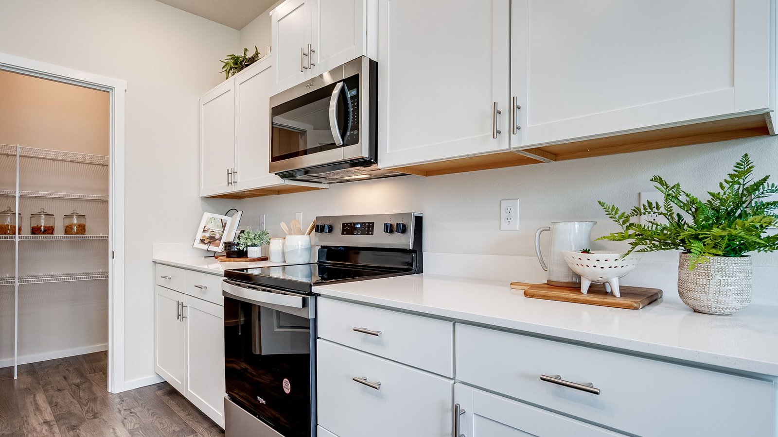 Kitchen with shaker cabinets, quartz counters, stainless steel appliances, pantry, and an island with a breakfast bar