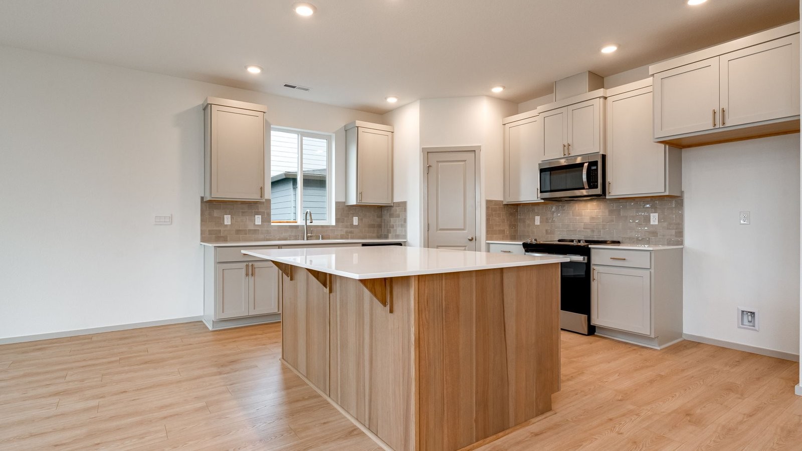 Kitchen with shaker cabinets, quartz counters, stainless steel appliances, pantry, and an island with a breakfast bar