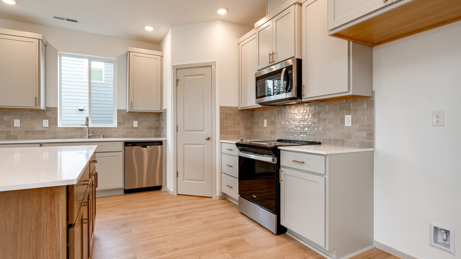 Kitchen with shaker cabinets, quartz counters, stainless steel appliances, pantry, and an island with a breakfast bar