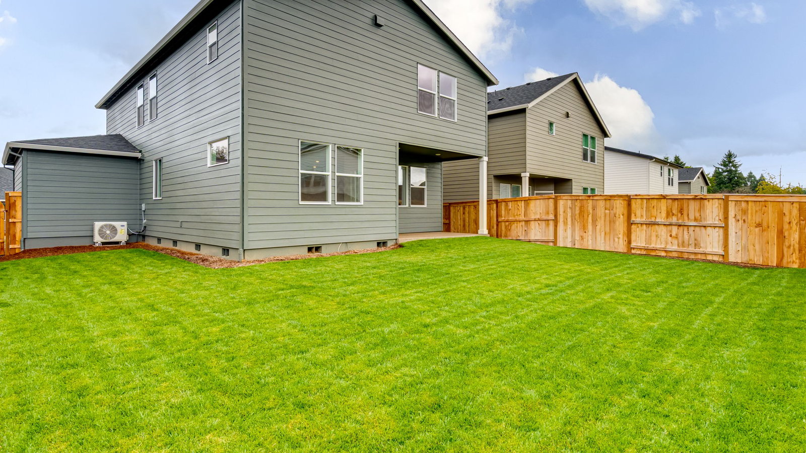 fully fenced backyard with sod lawn and a patio