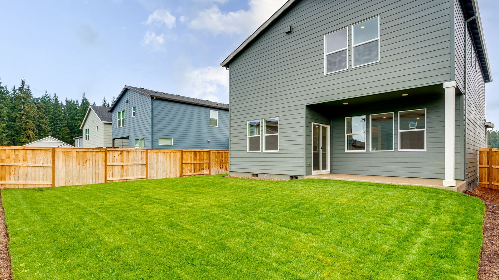 fully fenced backyard with sod lawn and a patio