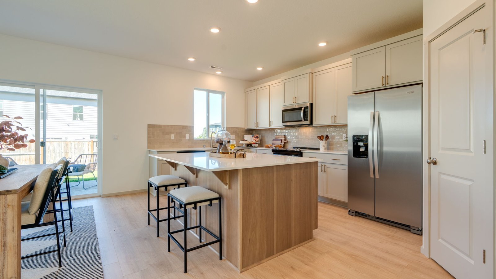 Kitchen with shaker cabinets, quartz counters, stainless steel appliances, pantry, and an island with a breakfast bar