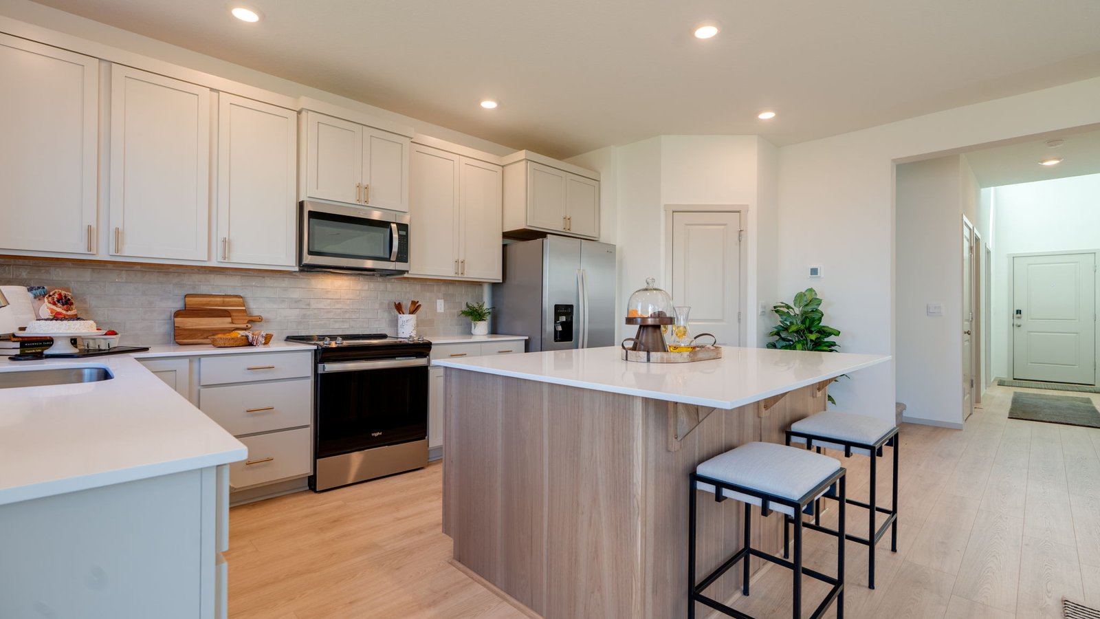 Kitchen with shaker cabinets, quartz counters, stainless steel appliances, pantry, and an island with a breakfast bar