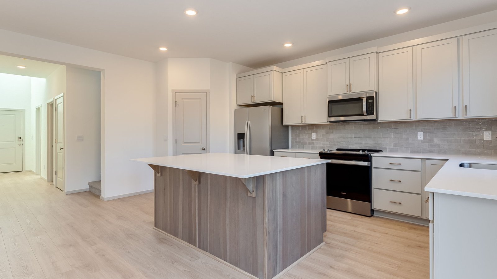 Kitchen with shaker cabinets, quartz counters, stainless steel appliances, pantry, and an island with a breakfast bar