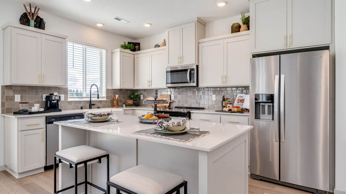 Kitchen with shaker cabinets, quartz counters, stainless steel appliances, pantry, and an island with a breakfast bar