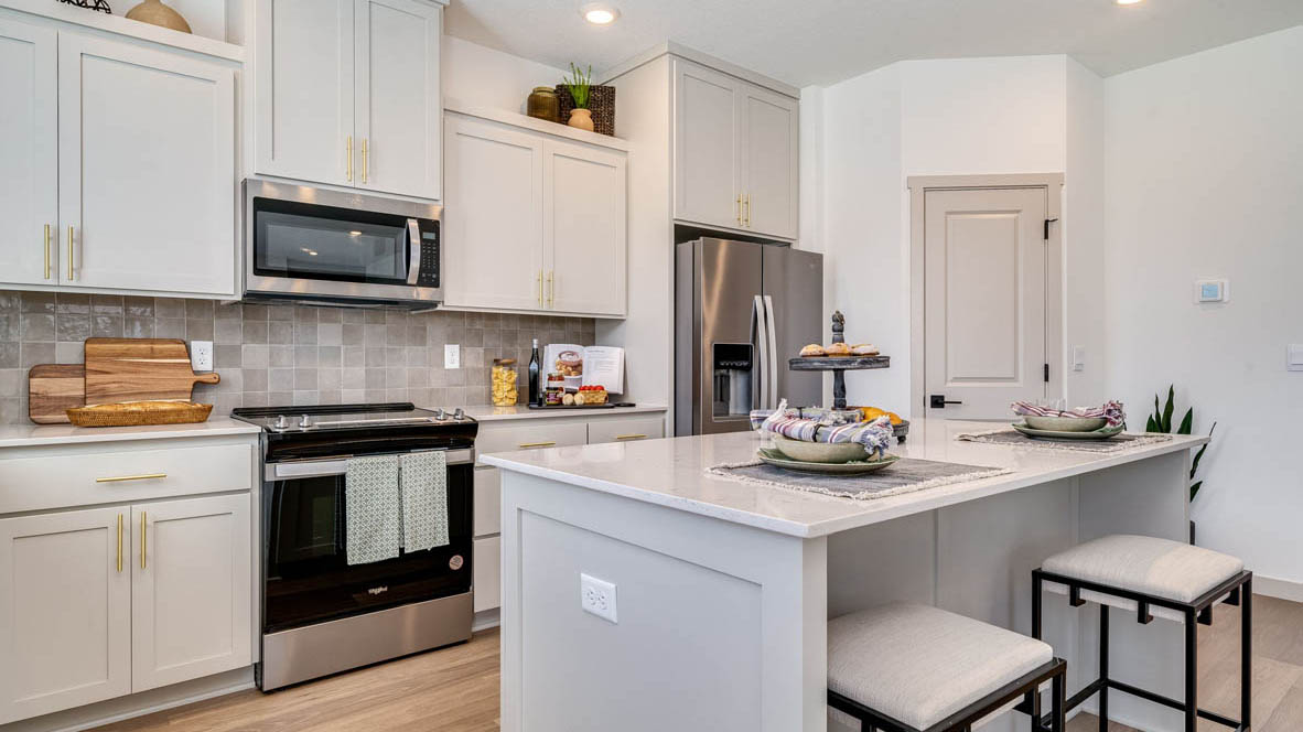 Kitchen with shaker cabinets, quartz counters, stainless steel appliances, pantry, and an island with a breakfast bar