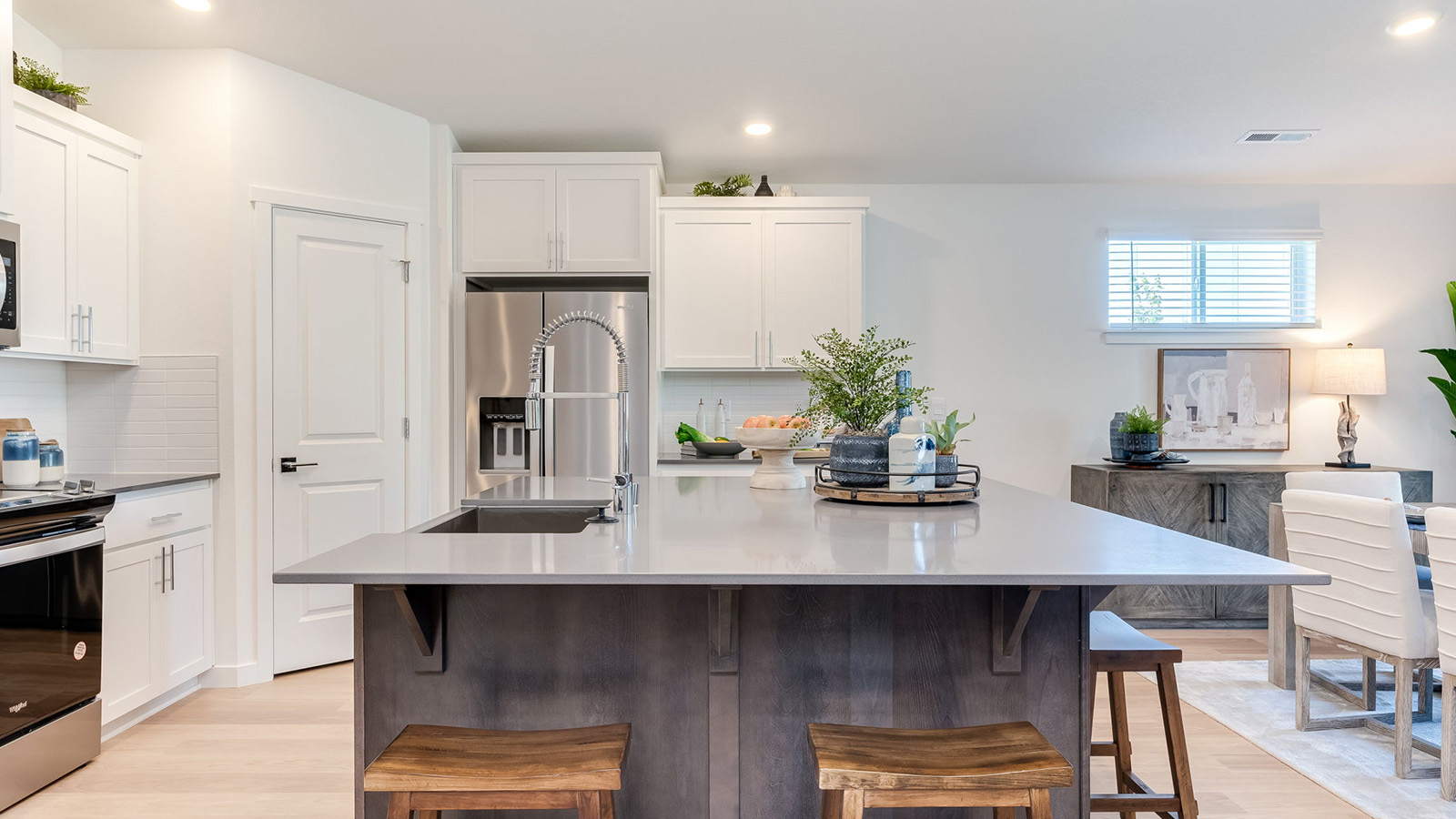 Kitchen with shaker cabinets, quartz counters, stainless steel appliances, pantry, and an island with a breakfast bar