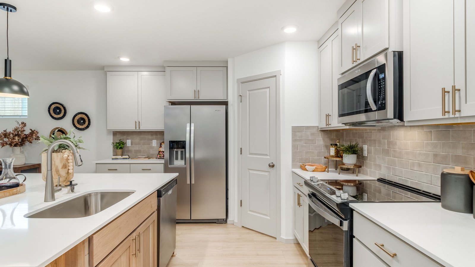 Kitchen with shaker cabinets, quartz counters, stainless steel appliances, pantry, and an island with a breakfast bar