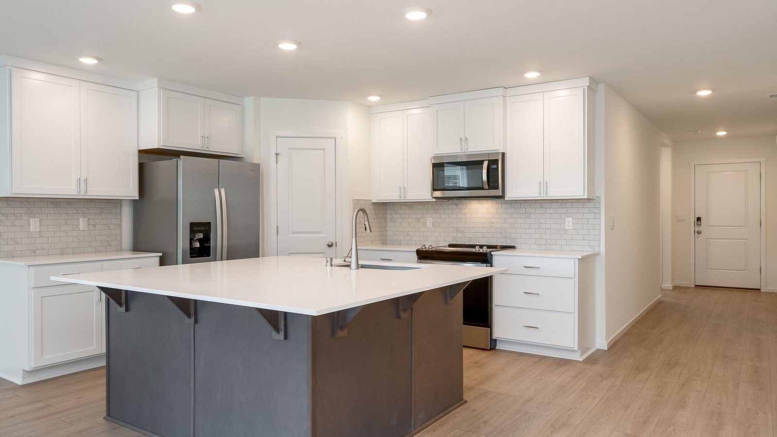 Kitchen with shaker cabinets, quartz counters, stainless steel appliances, pantry, and an island with a breakfast bar