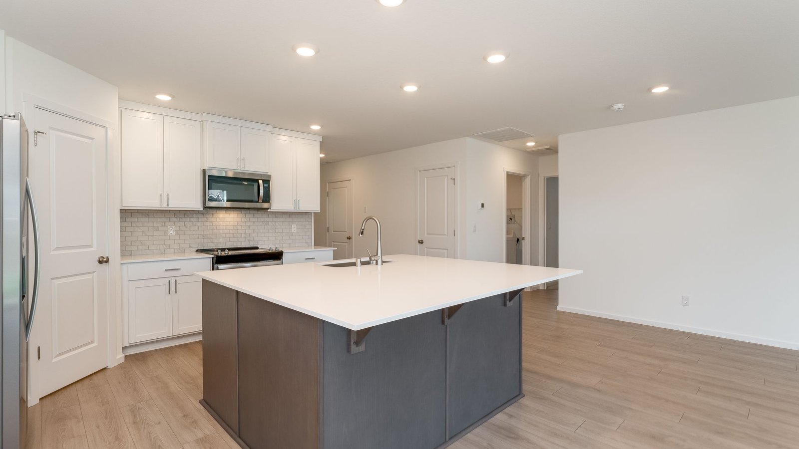 Kitchen with shaker cabinets, quartz counters, stainless steel appliances, pantry, and an island with a breakfast bar