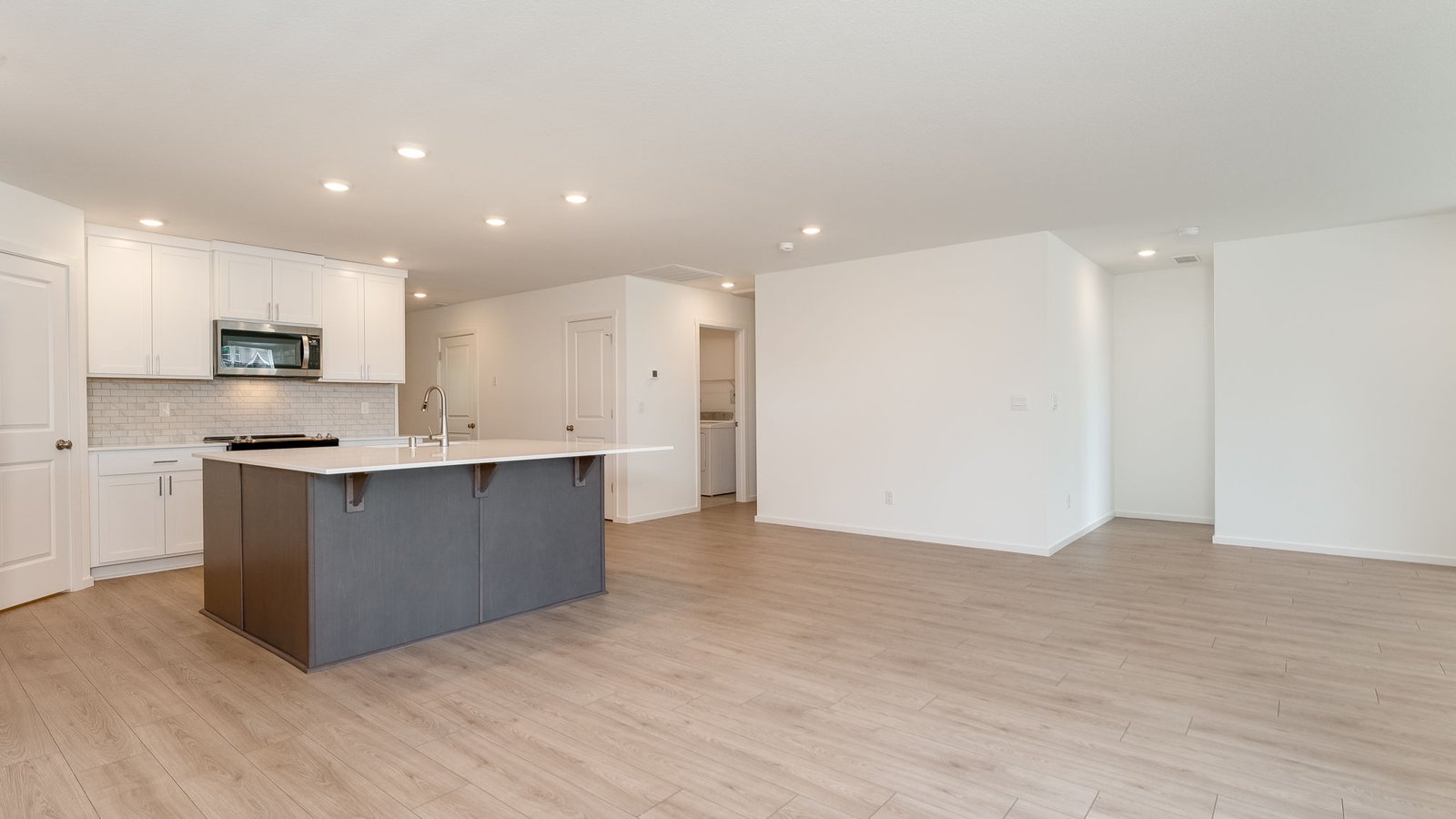 Kitchen with shaker cabinets, quartz counters, stainless steel appliances, pantry, and an island with a breakfast bar