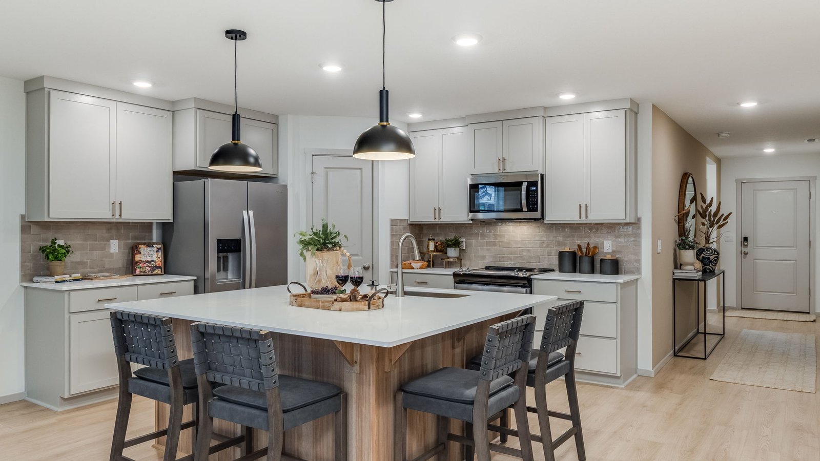 Kitchen with shaker cabinets, quartz counters, stainless steel appliances, pantry, and an island with a breakfast bar