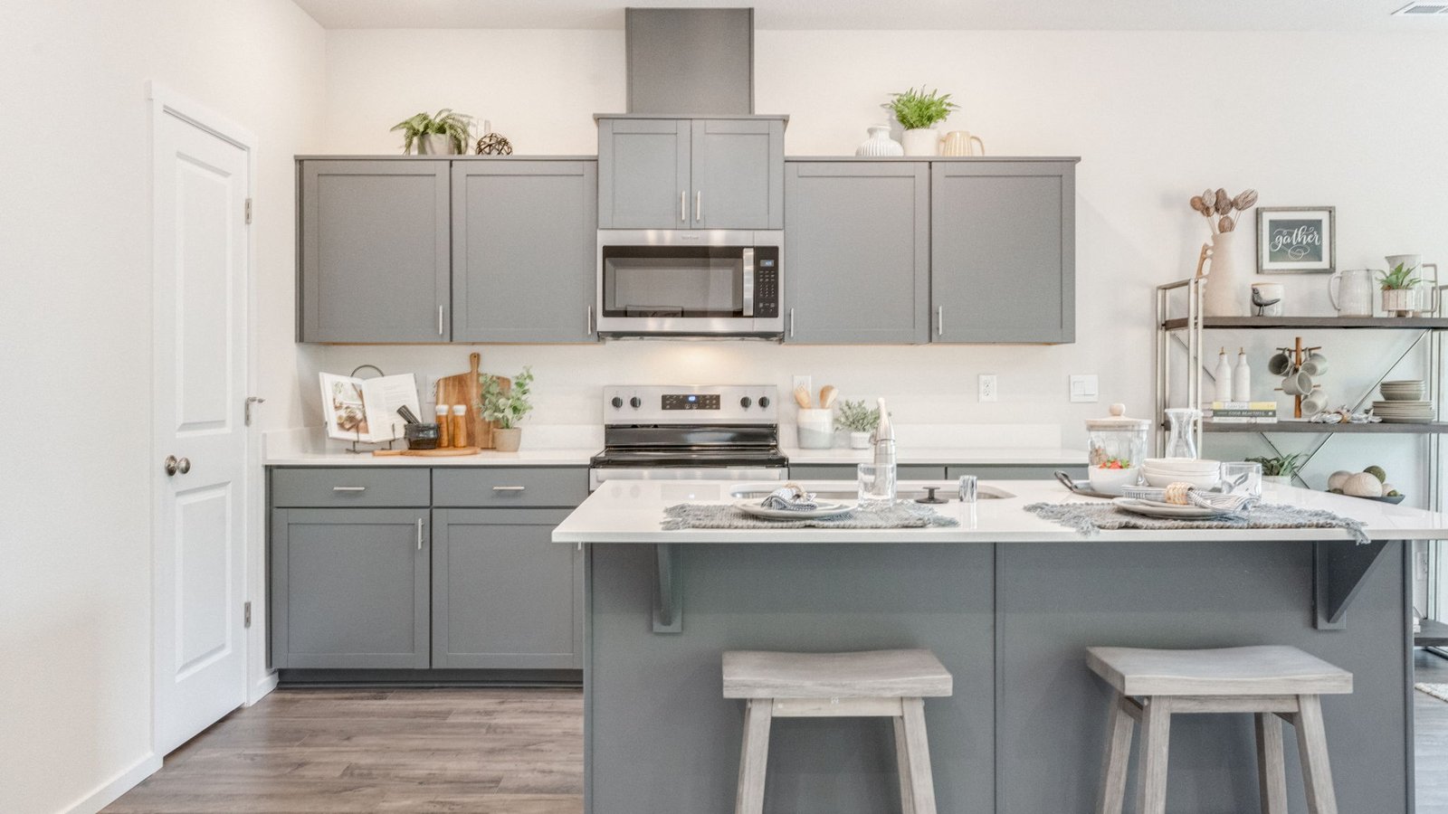 Kitchen with shaker cabinets, quartz counters, stainless steel appliances, pantry, and an island with a breakfast bar