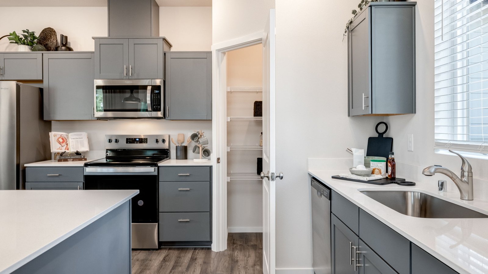 Kitchen with shaker cabinets, quartz counters, stainless steel appliances, pantry, and an island with a breakfast bar