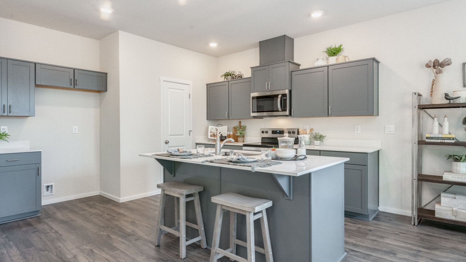 Kitchen with shaker cabinets, quartz counters, stainless steel appliances, pantry, and an island with a breakfast bar