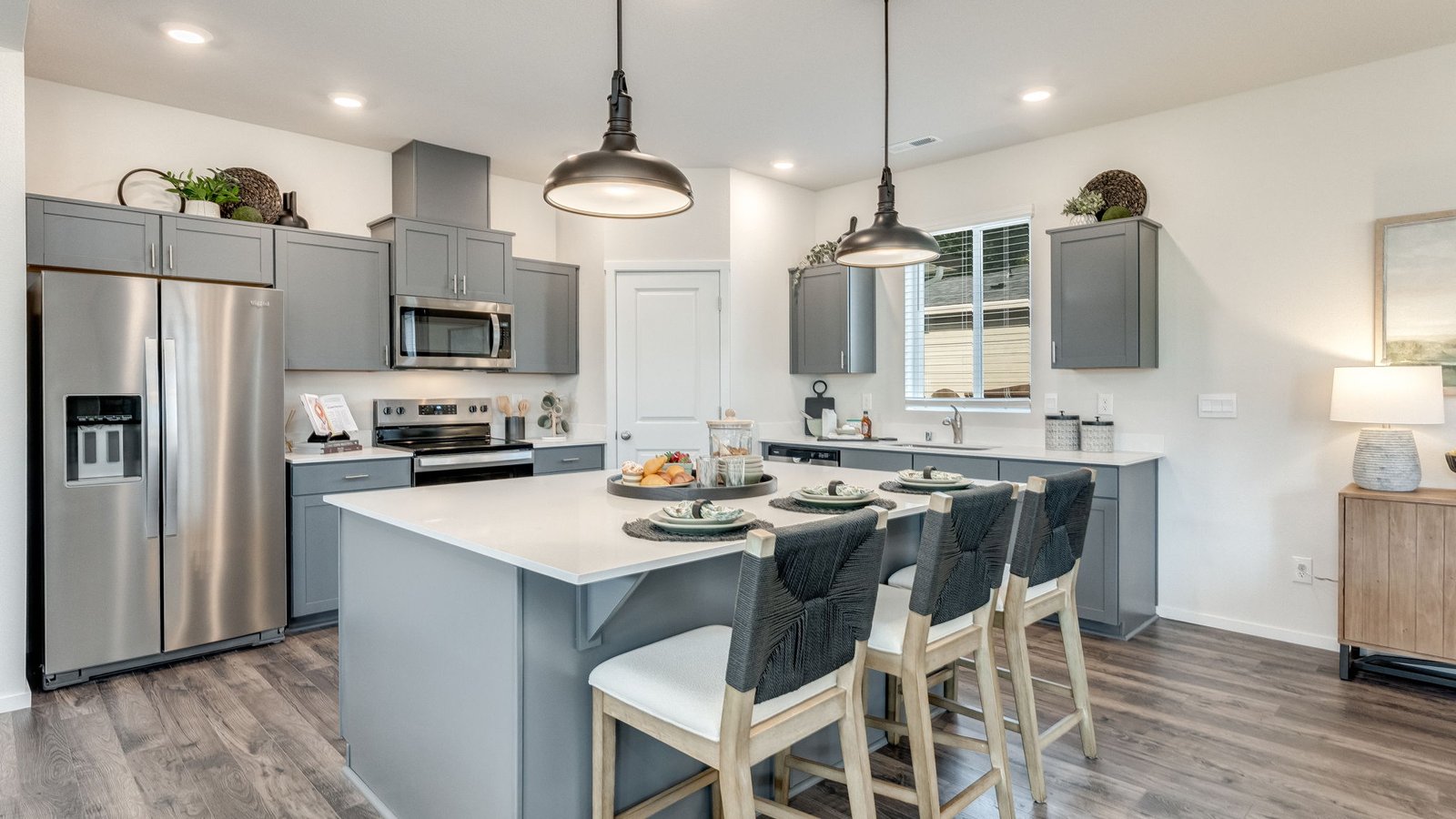 Kitchen with shaker cabinets, quartz counters, stainless steel appliances, pantry, and an island with a breakfast bar