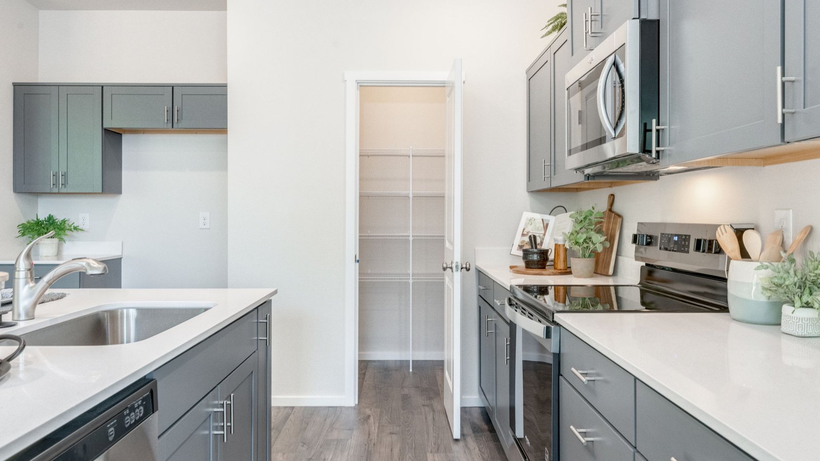 Kitchen with shaker cabinets, quartz counters, stainless steel appliances, pantry, and an island with a breakfast bar