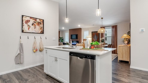 Kitchen with shaker cabinets, quartz counters, stainless steel appliances, pantry, and an island with a breakfast bar