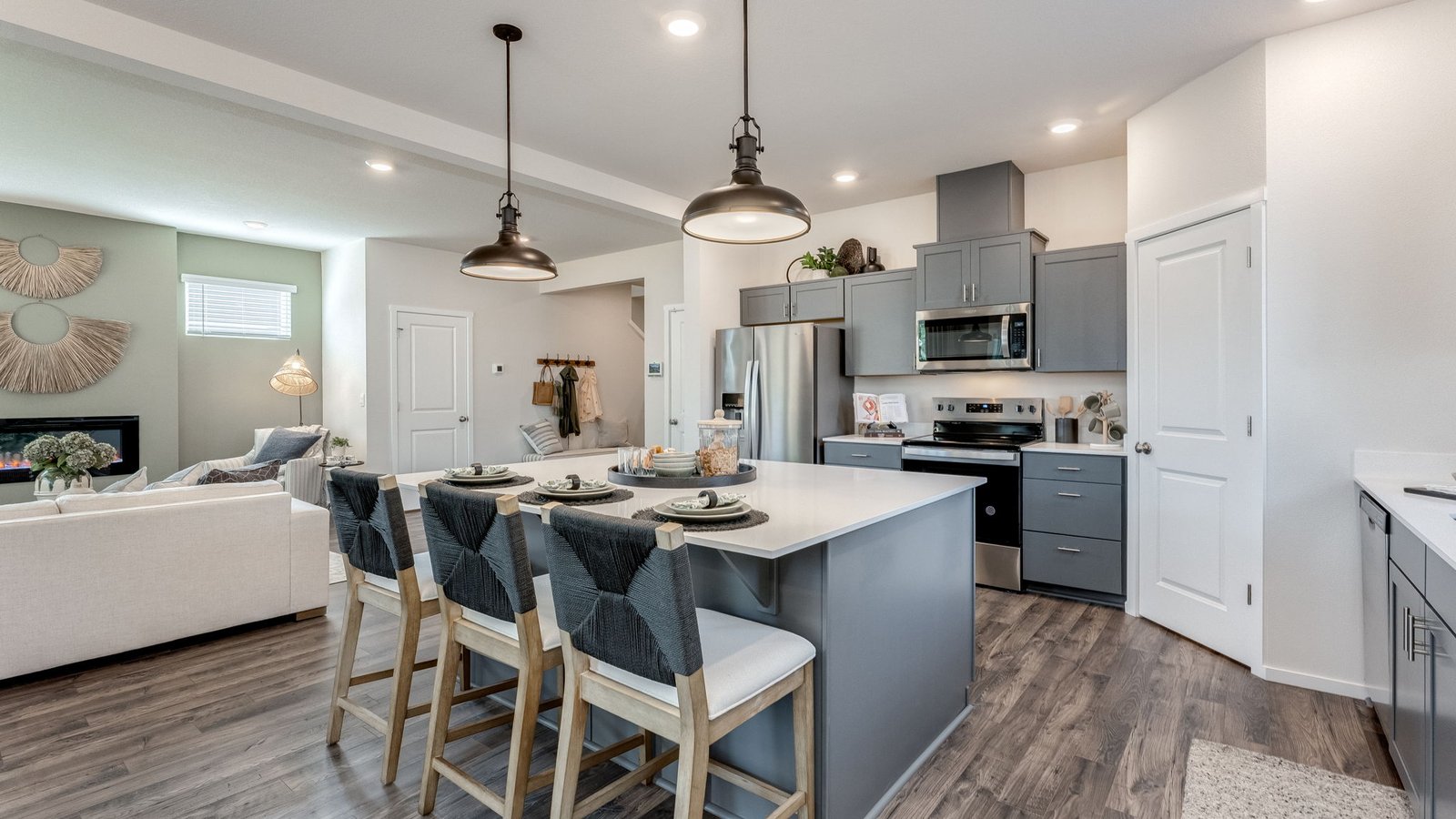 Kitchen with shaker cabinets, quartz counters, stainless steel appliances, pantry, and an island with a breakfast bar