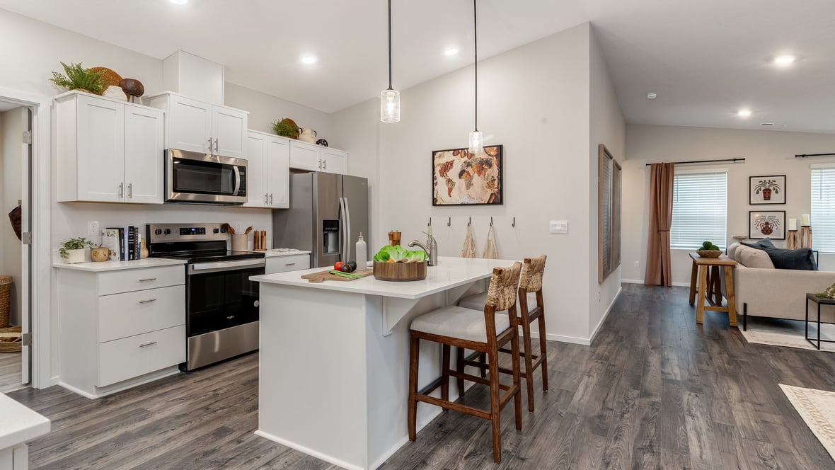 Kitchen with shaker cabinets, quartz counters, stainless steel appliances, pantry, and an island with a breakfast bar