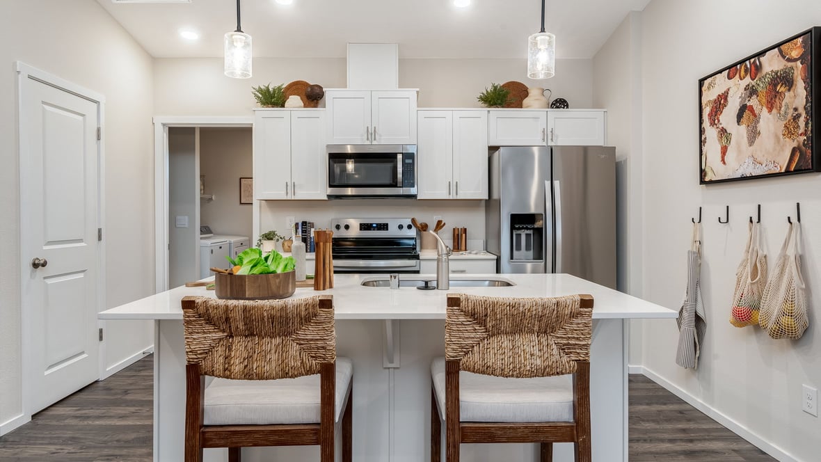 Kitchen with shaker cabinets, quartz counters, stainless steel appliances, pantry, and an island with a breakfast bar