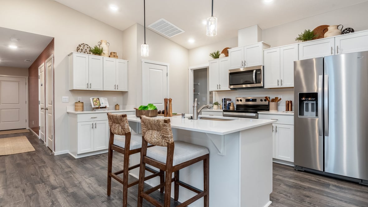 Kitchen with shaker cabinets, quartz counters, stainless steel appliances, pantry, and an island with a breakfast bar