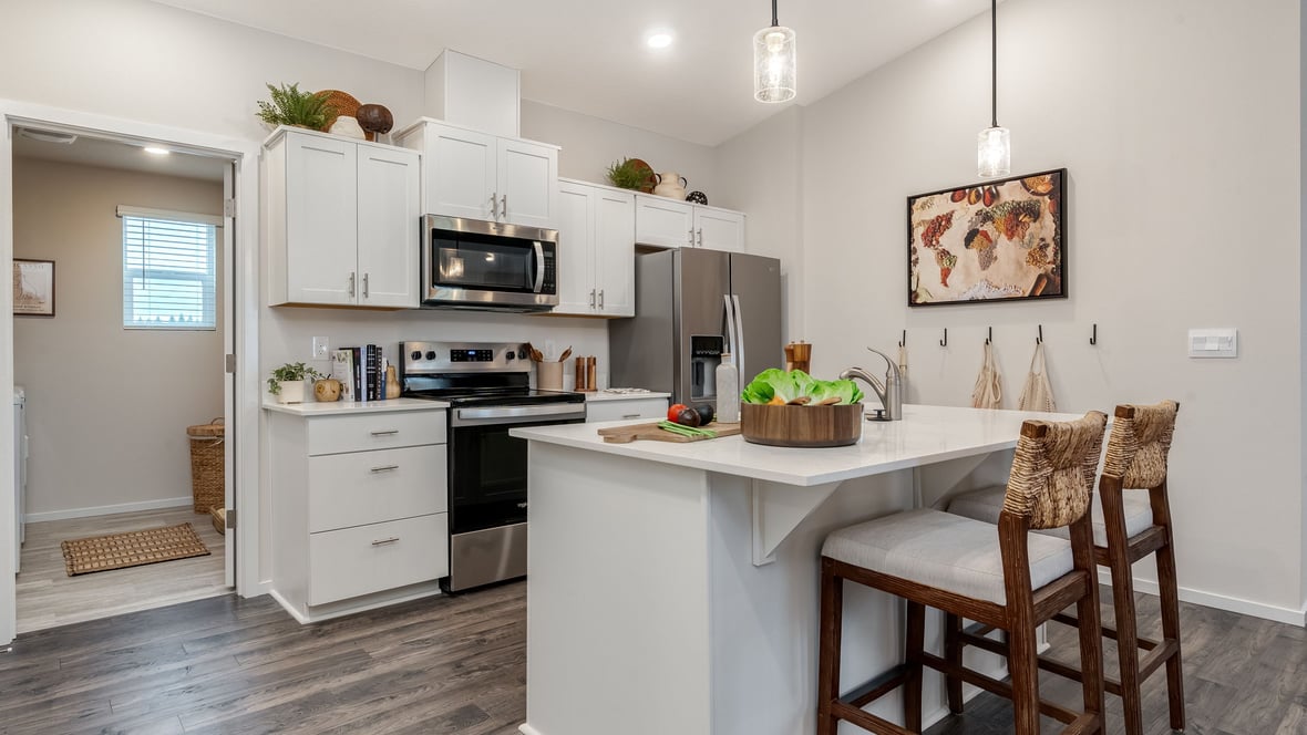 Kitchen with shaker cabinets, quartz counters, stainless steel appliances, pantry, and an island with a breakfast bar
