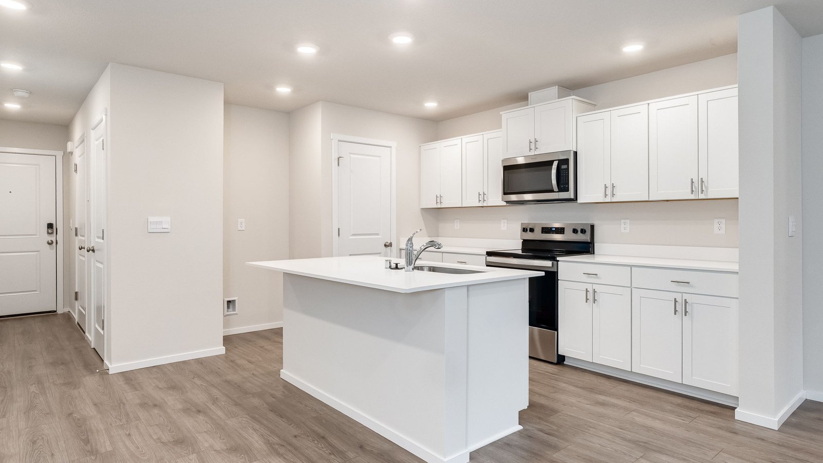 Kitchen with shaker cabinets, quartz counters, stainless steel appliances, pantry, and an island with a breakfast bar