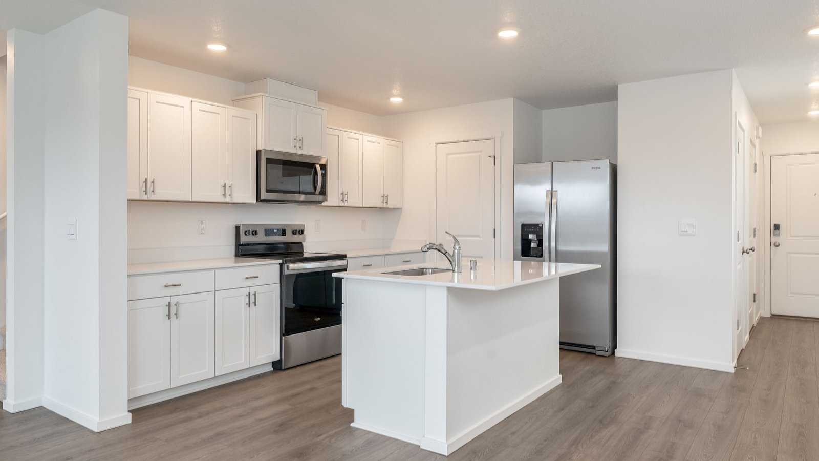 Kitchen with shaker cabinets, quartz counters, stainless steel appliances, pantry, and an island with a breakfast bar