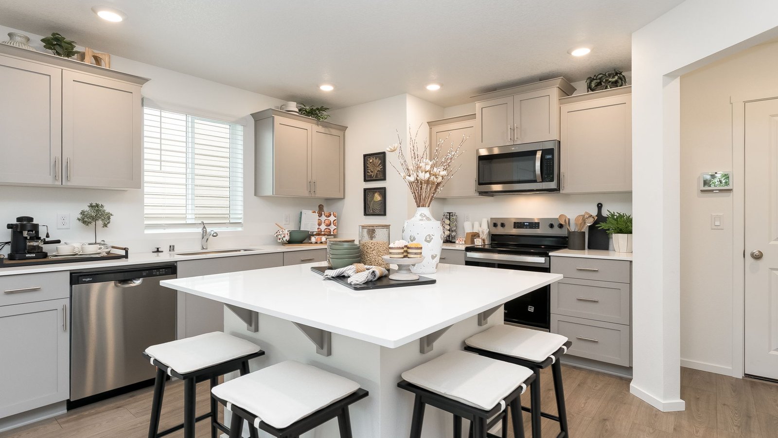 Kitchen with shaker cabinets, quartz counters, stainless steel appliances, pantry, and an island with a breakfast bar
