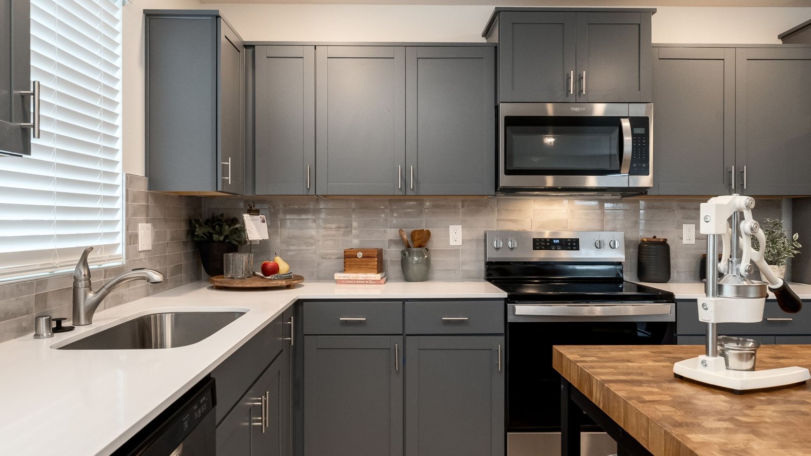 L-shaped kitchen with shaker cabinets, quartz counters, stainless steel appliances, and a pantry