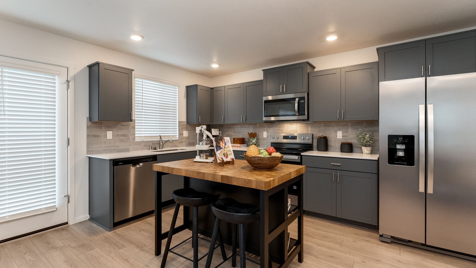 L-shaped kitchen with shaker cabinets, quartz counters, stainless steel appliances, and a pantry