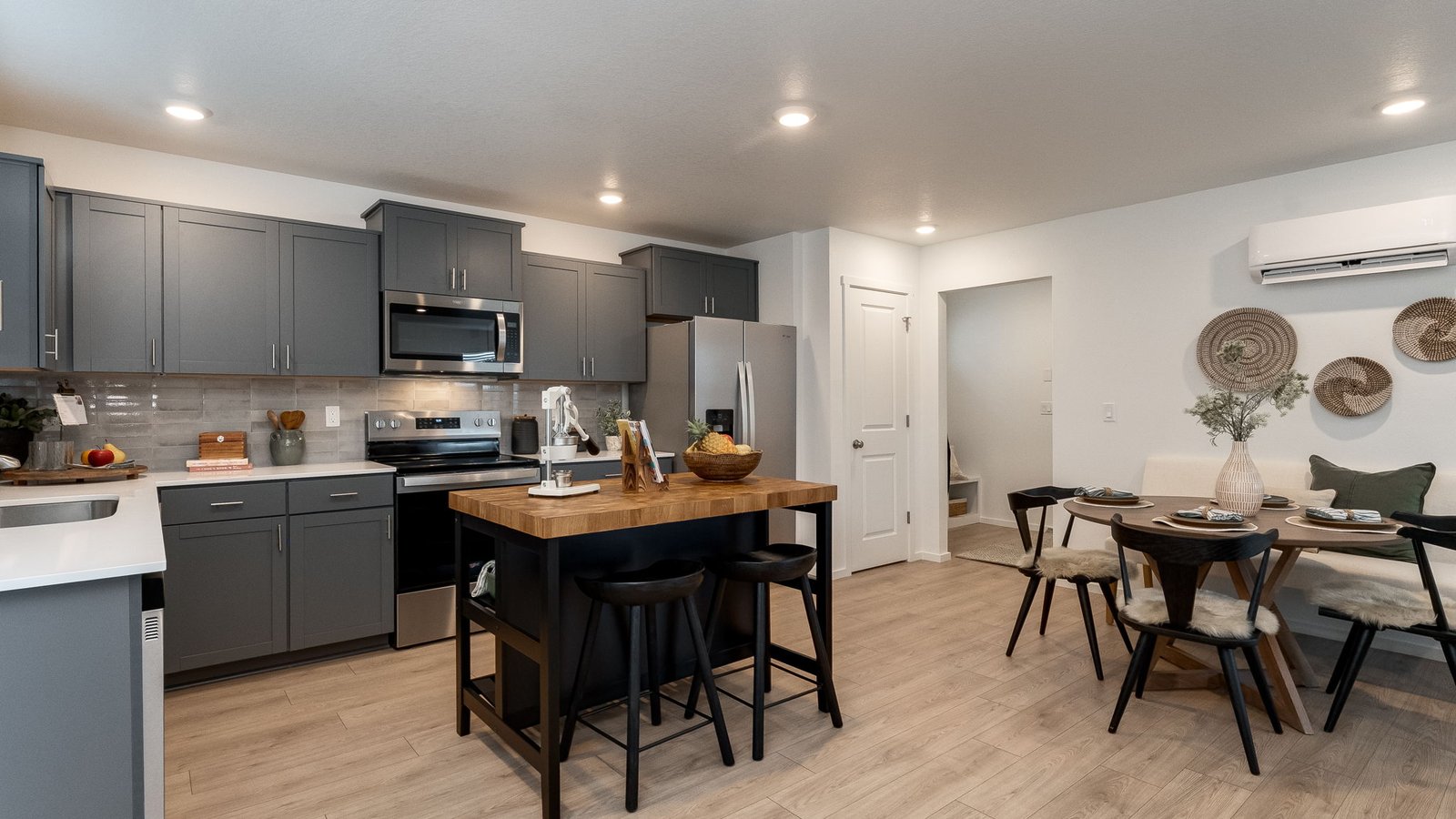 L-shaped kitchen with shaker cabinets, quartz counters, stainless steel appliances, and a pantry