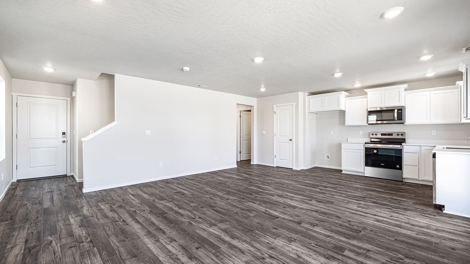 L-shaped kitchen with shaker cabinets, quartz counters, stainless steel appliances, and a pantry